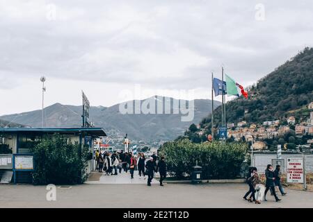 Como, région Lombardie, Italie - 14 janvier 2021 : touristes marchant dans le port du lac de Côme, quai du ferry dans la sombre journée d'hiver. Location de bateau pour les touristes et Banque D'Images