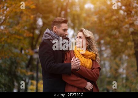 Portrait d'un couple amoureux. Un beau homme et une femme se sont embrassés de derrière le sourire en regardant les uns les autres dans le parc d'automne. Photo d'un jeune en plein air Banque D'Images