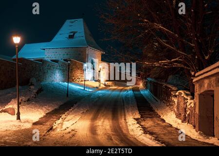 Bastion du mur défensif médiéval de Vilnius dans la vieille ville de Vilnius, vue de nuit ou de soir avec de vieux bâtiments et une lampe de rue en hiver avec de la neige Banque D'Images