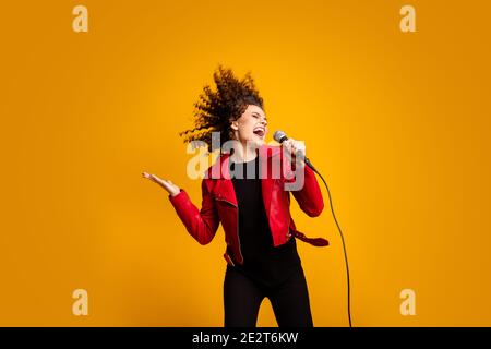 Portrait d'une jolie fille à poil ondulé populaire, soliste, choriste, choriste isolé sur fond jaune vif Banque D'Images