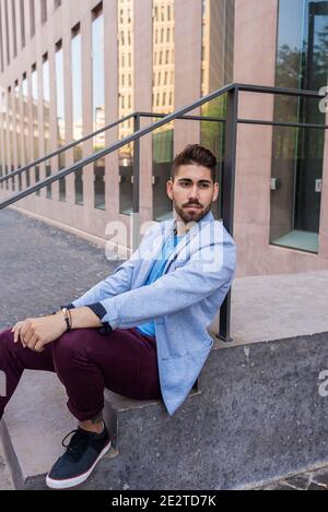 Joyeux jeune homme à barbe assis sur des marches Banque D'Images