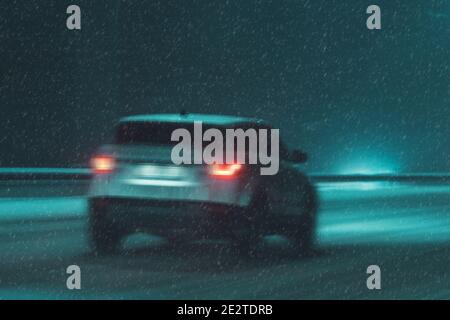 la voiture roule la nuit sur une route enneigée Banque D'Images