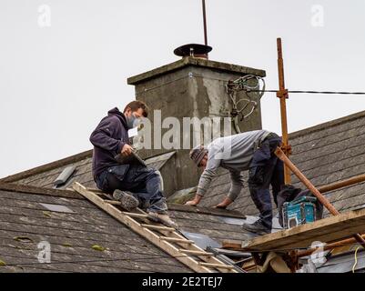 Constructeur travaillant un toit portant un masque de visage covid Banque D'Images