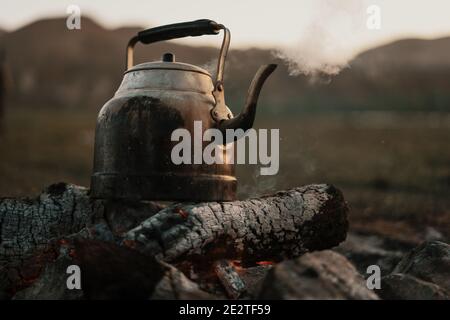 Gros plan Old kettle chauffé sur un feu de joie sur un pré de montagne verte. Voyage épique dans les montagnes. Banque D'Images