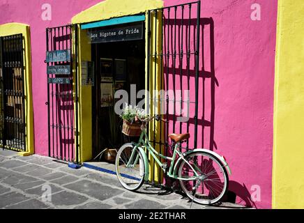 Fleuriste dans la célèbre allée des grenouilles avec un mur en stuc peint rose et un vélo d'époque à l'entrée de Puebla de Zaragoza, au Mexique. Banque D'Images