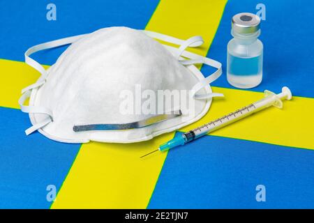 Drapeau suédois, masque facial n95, seringue à aiguille et flacon. Concept de distribution du vaccin contre le coronavirus Covid-19, pénurie d'approvisionnement et crise des soins de santé Banque D'Images