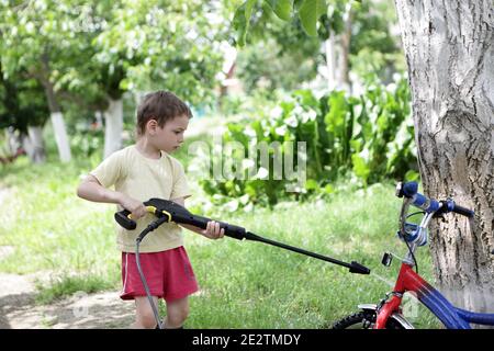 Vélo de lavage pour enfants avec nettoyeur haute pression Banque D'Images