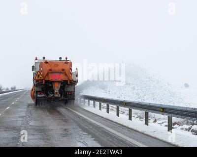 Chasse-neige travaillant sur la chaussée glacée, expulsant la neige enlevée vers l'extérieur Banque D'Images