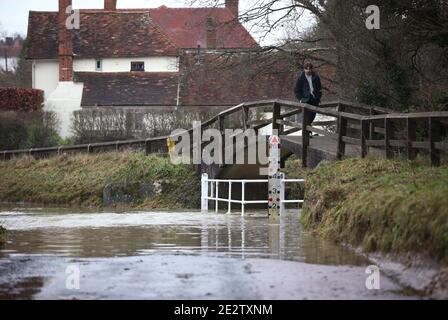 Un homme traverse un pont au-dessus d'une route inondée dans le village de Great Easton, Dunmow, où la rivière Chelmer éclate ses rives. Des avertissements d'inondation ont été émis vendredi dans de grandes parties de l'Angleterre à la suite de fortes pluies. Banque D'Images