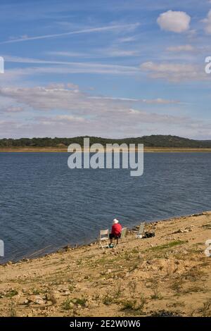 Femme de race blanche assise sur une chaise avec un chapeau de paille sur un réservoir de lac de barrage à Alentejo, Portugal Banque D'Images
