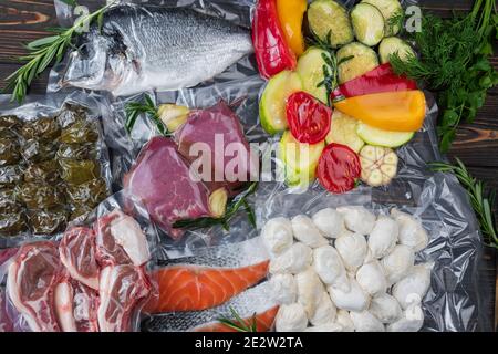 Produits en conditionnement sous vide, sur une planche en bois. Légumes, viande de poisson, dolma, kurza. Pandémie de quarantaine Banque D'Images