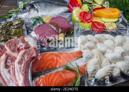 Produits en conditionnement sous vide, sur une planche en bois. Légumes, viande de poisson, dolma, kurza. Pandémie de quarantaine Banque D'Images