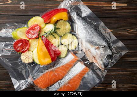 Produits en conditionnement sous vide, sur une planche en bois. Légumes, viande de poisson, dolma, kurza. Pandémie de quarantaine Banque D'Images