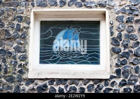 Fenêtre en vitraux représentant un navire sur le mur de silex de York Gate House à Broadlairs, île de Thanet, Kent, Royaume-Uni Banque D'Images