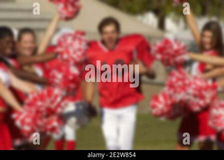 Joueur de football qui traverse Cheerleaders Banque D'Images