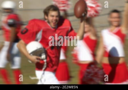 Joueur de football heureux tournant par Cheerleaders Banque D'Images