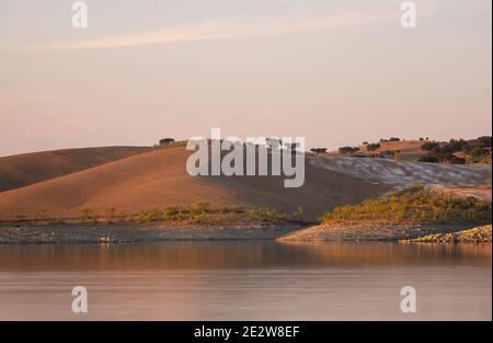 Paysage de collines désertiques avec réflexion sur l'eau sur un barrage lac réservoir au coucher du soleil à Terena, Portugal Banque D'Images