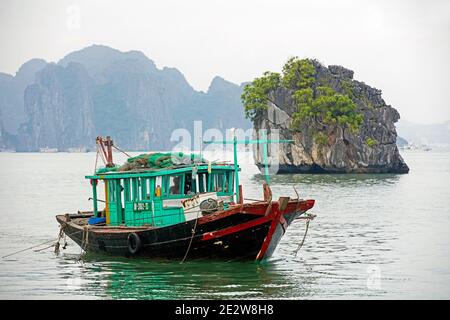 Bateau de pêche en bois et îles monolithiques en calcaire dans la baie d'Ha long / baie d'Halong / Vinh Ha long, province de Quang Ninh, Vietnam Banque D'Images