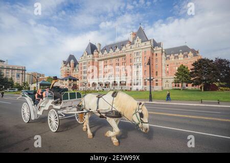 Victoria, Canada - juin 6 2017 : les touristes profitent d'une promenade en calèche en face de l'hôtel Fairmont Empress, le long du port intérieur de Victo Banque D'Images