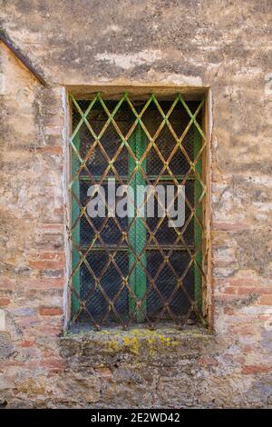 Une fenêtre barrée dans un bâtiment résidentiel dans le centre historique de la ville médiévale de Monticchiello près de Pienza dans la province de Sienne, Toscane, Italie Banque D'Images