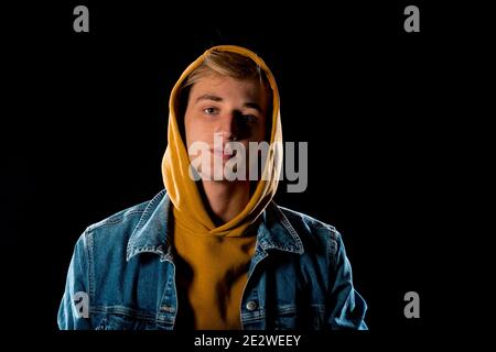 Cool jeune homme vêtu d'une veste Jean et d'un pull à capuche jaune Banque D'Images