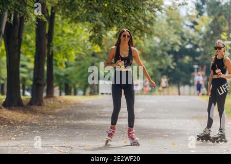 Femme sportive chaude en rollerblading sportswear au parc par temps ensoleillé. Banque D'Images