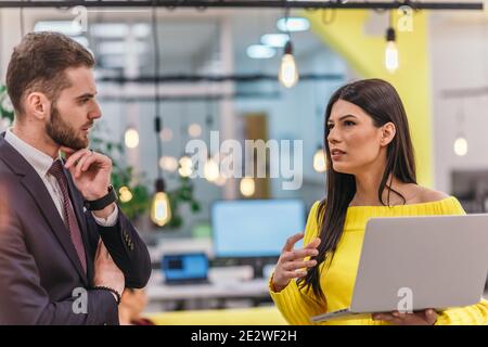 Le responsable explique à son employé comment terminer ses tâches. Collègues discutant d'un projet en se tenant dans un bureau. Banque D'Images
