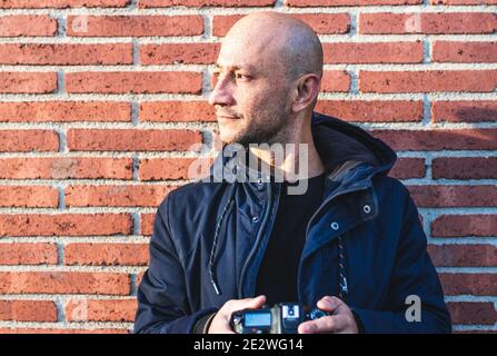 Homme posant séductivement regardant à côté d'un Orange Mur de briques Banque D'Images