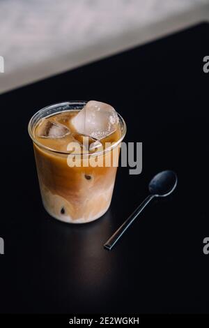 Café glacé de spécialité sur table noire avec cuillère noire Banque D'Images