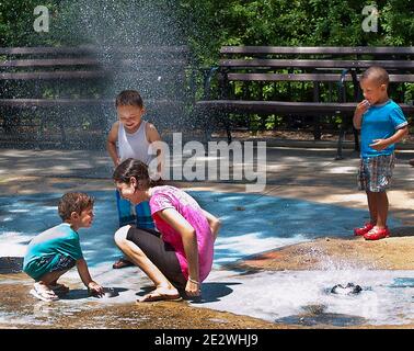 Enfants au parc jouant avec le bec verseur d'eau Banque D'Images
