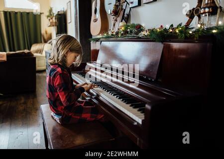 Petit garçon jouant du piano avec de la verdure de noël Banque D'Images