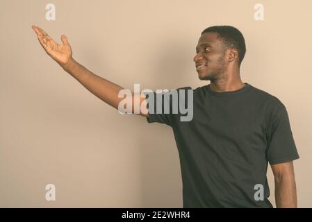 Jeune homme africain portant chemise noire contre l'arrière-plan gris Banque D'Images