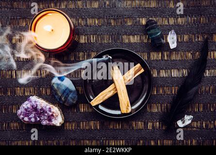 Vue sur la plate de la pose du bois de Palo Santo connu comme le bois Saint aromatique huileux bâtons couvant sur la plaque sur la table de nettoyage à la maison concept d'énergie négative. Banque D'Images