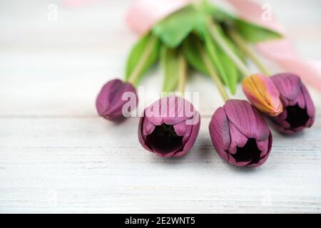 Cinq tulipes violettes se trouvent sur une table en bois clair. Vue latérale, gros plan. Banque D'Images