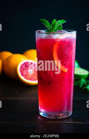 Mojito d'Orange Blood et de framboise : cocktail de rhum avec des oranges sanguines, des framboises, de la chaux et des feuilles de menthe servies dans un grand verre sur glace Banque D'Images