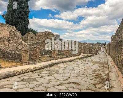Vider l'ancienne ville romaine de Pompéi sous un ciel bleu avec des nuages. Panorama d'une rue abandonnée à Pompéi. Ruines de la ville, route pavée Banque D'Images