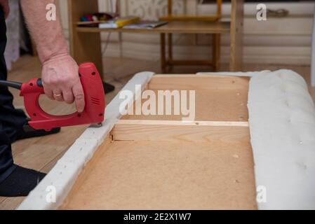 Utilisation d'une agrafeuse. Bricolage. Réparer le canapé. Meubles souples et extensibles. Banque D'Images