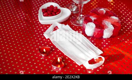 Table de concept de Saint Valentin. Dîner romantique avec masque médical. Coronavirus 2021. Masque de protection du visage et réglage de la table rouge Banque D'Images