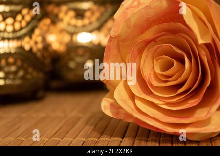 Gros plan de fleurs de rose en papier couché sur une table en bois avec des bougies ornementales floues en arrière-plan. Concept bien-être Banque D'Images