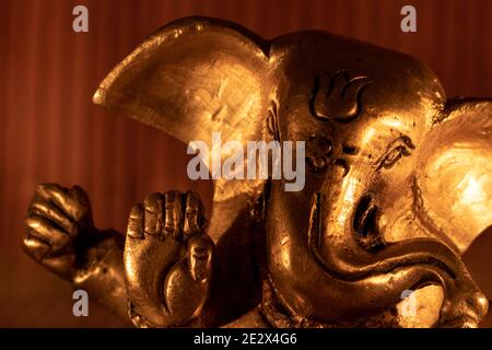 Gros plan d'une statue Golden Lord Ganesha avec éclairage ambiant chaud Banque D'Images