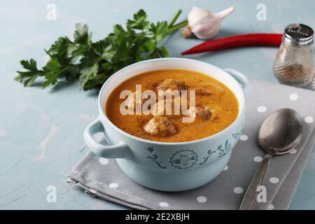 Soupe de crème de citrouille avec boulettes de viande dans un bol sur fond bleu clair, format horizontal, gros plan Banque D'Images