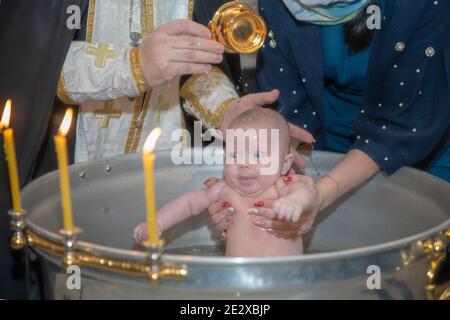 Bébé baptisé dans le bol de baptême de l'église. Banque D'Images