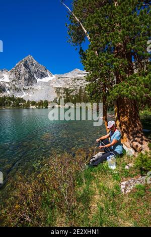 Eau de randonnée purifiante sur les rives du lac Treasure, John Muir Wilderness, Sierra Nevada Mountains, Californie États-Unis Banque D'Images