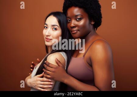 jeune femme asiatique et afro posant joyeuse ensemble sur fond marron, style de vie diverse nationalité concept de personnes Banque D'Images