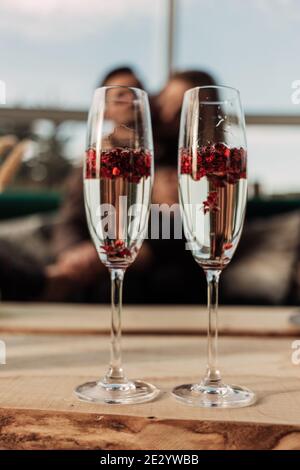 Concept de célébration de la Saint Valentin heureux. Gros plan de 2 deux verres avec champagne pétillant et confetti en forme de coeur rouge. Potion d'amour en verre Banque D'Images