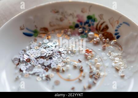 Perles, paillettes, perles de verre sur une soucoupe avec peinture. Gros plan Banque D'Images