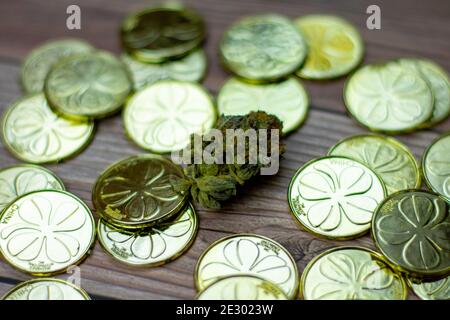 Un Nugget coloré de Cannabis entouré par une pile de Saint Pièces d'or de la journée de Pattys Banque D'Images