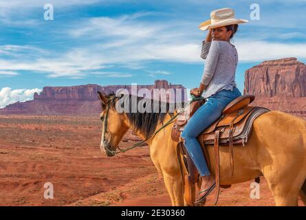Jeune Afro-américaine à cheval par John Ford point de vue avec West Mitten butte et Mitchell mesa, Monument Valley Navajo Tribal Park, États-Unis. Banque D'Images