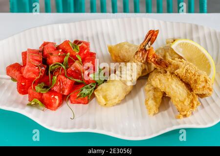 Crevettes battues, salade avec pastèque et menthe fraîches et citron. Servi sur une plaque en céramique blanche. Banque D'Images