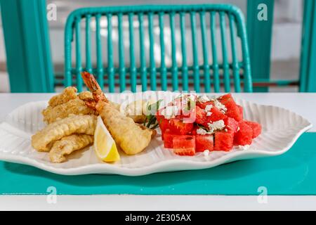 Crevettes battues, salade avec pastèque fraîche, menthe et feta, citron. Servi sur une plaque en céramique blanche. Banque D'Images